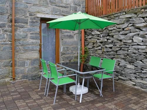 a table with green chairs and an umbrella at Llwyn Rhedyn in Blaenau-Ffestiniog