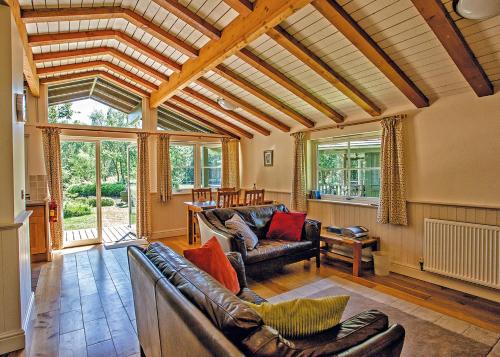 a living room with leather furniture and a large window at Great Wood Lodges in Flaxton