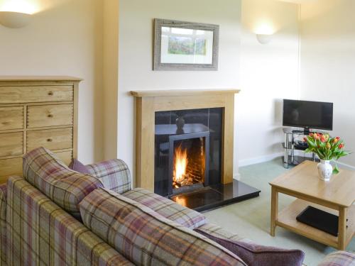 a living room with a couch and a fireplace at North Farm Bungalow in Horsley