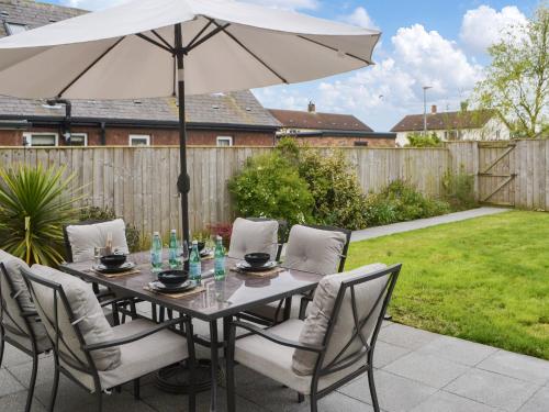 a table and chairs with an umbrella on a patio at Lyndhurst in Longhorsley