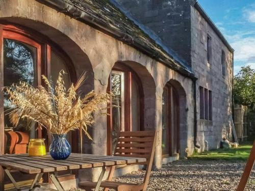 een houten tafel met een vaas erop naast een gebouw bij Farmtoun Cottage in Forfar