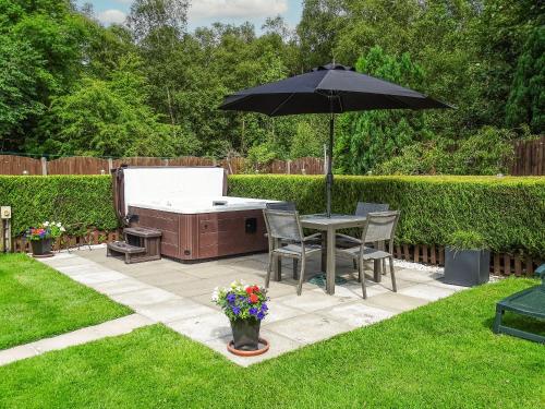 - une table et des chaises sous un parasol dans la cour dans l'établissement Blaeberry Cottage - 28061, à Dinwoodie Mains