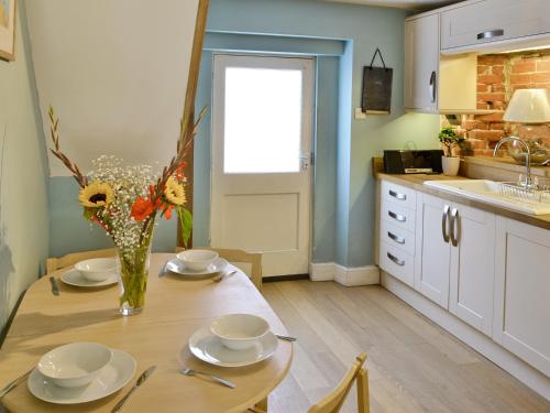 a kitchen with a table with plates and flowers on it at Seashells in Cromer