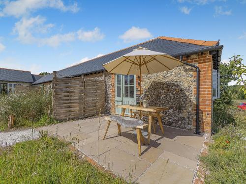 a table and an umbrella in front of a building at Dunnock - Uk50146 in Faversham