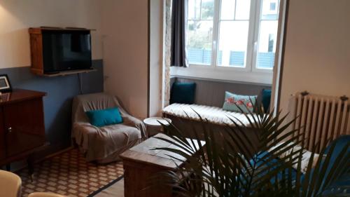 a living room with a couch and a tv at Villa de 1926, plage de sable fin à 200m, proche commerces in Jullouville-les-Pins