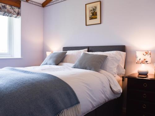 a bedroom with a bed with white sheets and pillows at Little Folly in  Liscombe