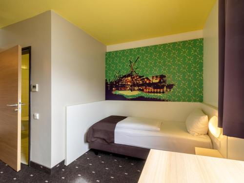 a bedroom with a bed and a painting on the wall at B&B Hotel Oberhausen am Centro in Oberhausen