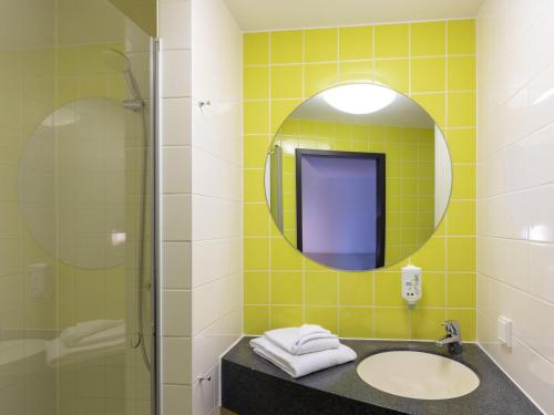 a bathroom with a sink and a mirror at B&B Hotel Oberhausen am Centro in Oberhausen