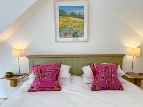 a bed with two pink pillows on top of it at Crown Lodge, Great Glemham in Saxmundham