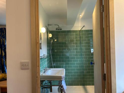 a bathroom with a sink and a green tiled wall at Crown Lodge, Great Glemham in Saxmundham