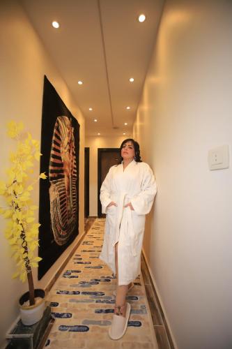 a woman in a white robe standing in a hallway at Happy Day Pyramids View Hotel in Cairo