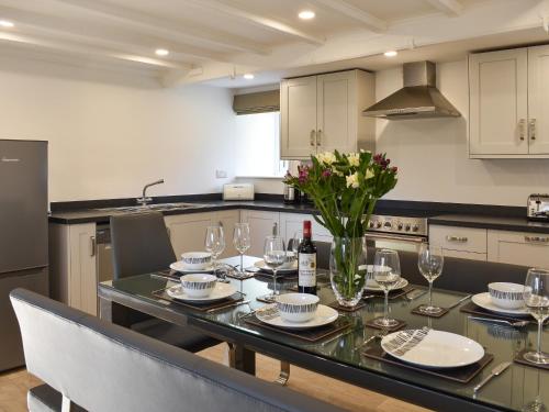 a kitchen with a table with wine glasses and flowers at Thistle Cottage in Carlton
