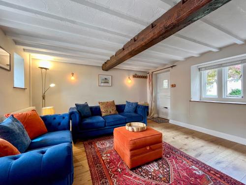 ein Wohnzimmer mit blauen Sofas und einem roten Teppich in der Unterkunft Oasis Cottage in Broughton Gifford