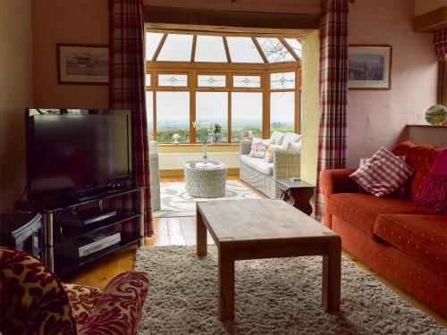 ein Wohnzimmer mit Sofa und Fernseher in der Unterkunft Barns End Cottage in Ludchurch