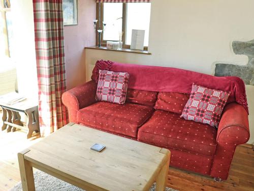 ein rotes Sofa im Wohnzimmer mit Couchtisch in der Unterkunft Barns End Cottage in Ludchurch