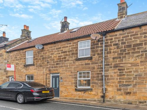 una macchina nera parcheggiata di fronte a un edificio di mattoni di Percy's Cottage a Castleton