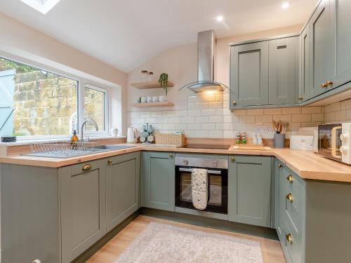 a kitchen with green cabinets and a sink at Percy's Cottage in Castleton