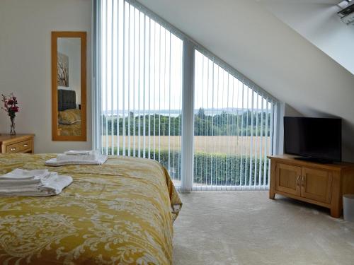 a bedroom with a bed and a large window at The Steading in Montrose
