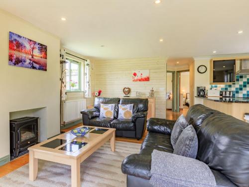 a living room with a leather couch and a coffee table at Primrose Lodge in Holsworthy