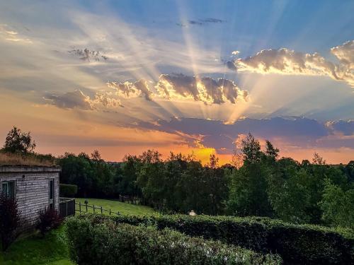 a sunset over a field with a building and trees at Primrose Lodge in Holsworthy
