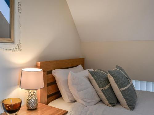 a bed with pillows and a table with a lamp at The Police Station - Uk45642 in Silloth