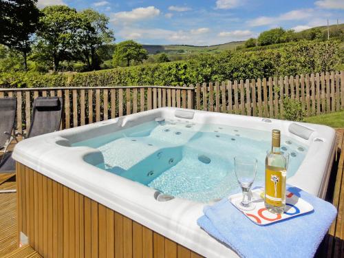 a hot tub with a bottle of wine and a glass at Ash Lodge - Hw7442 in Nantmel