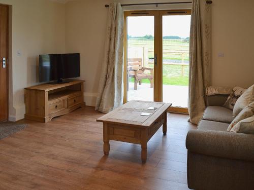 a living room with a tv and a couch and a table at Saddlers Cottage in Alkham