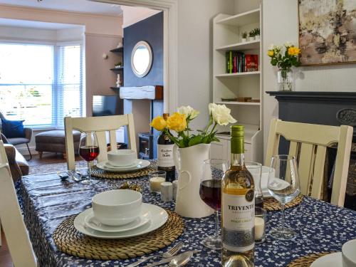 a dining room table with a bottle of wine and flowers at Mere Walk in Hornsea