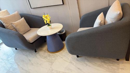 two chairs and a table with a vase of flowers on it at المنظر الجميل للشقق الفندقية in Al Jubail
