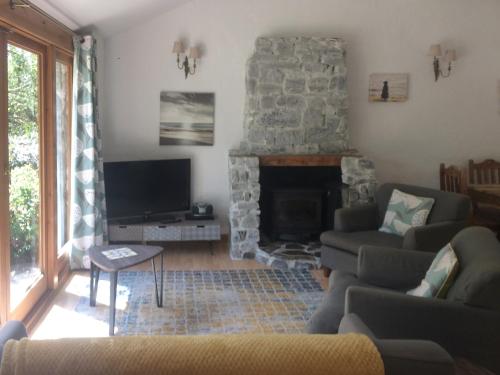 a living room with a stone fireplace and a tv at Oaktree Cottage in Appledore