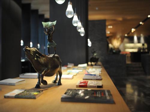 a statue of a frog on a table with books at Hotel Dùa in Kaohsiung