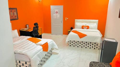two beds in a room with orange walls at Hôtel résidence Teranga confort in Thiès