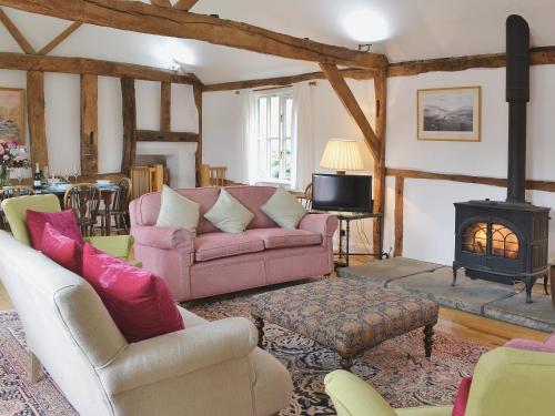 a living room with a pink couch and a fireplace at Priory Barn in Weald