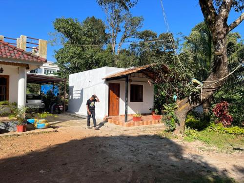 a man standing outside of a small house at Coorg Mountain Breeze Homestay in Madikeri
