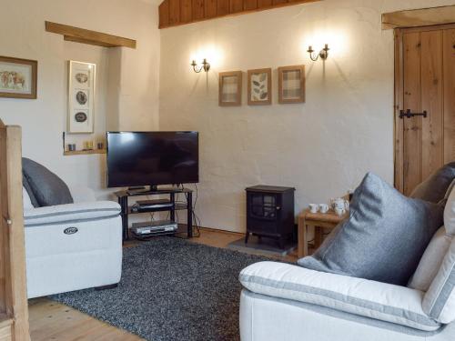 ein Wohnzimmer mit Sofa und Fernseher in der Unterkunft Hayloft Cottage in Ludchurch