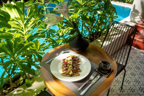 a plate of food on a table with a vase at Tropical An Bang Beach Villa in Hoi An