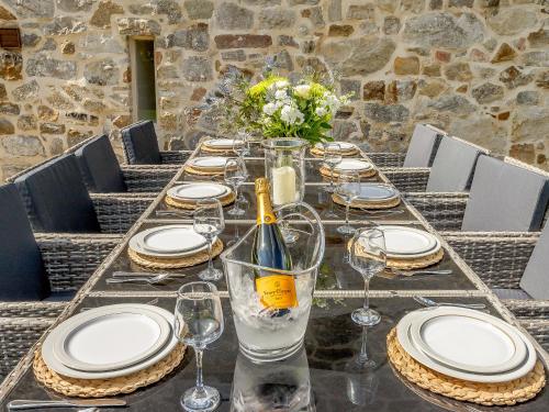 a table with glasses and plates and a bottle of wine at Waterside Barn in Bradbourne