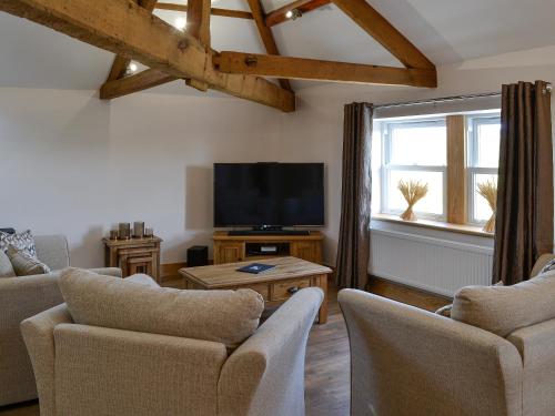 Una sala de estar con televisión, sofá y sillas. en Greengill Farm Holiday Cottage - Ukc2768, en Gilcrux