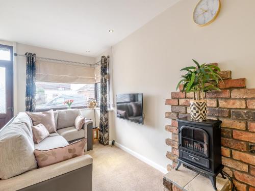 a living room with a couch and a brick fireplace at Tulip - Uk48836 in Skegness