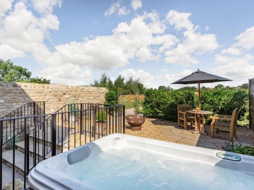 bañera de hidromasaje en un patio con sombrilla en The Granary - Uk40457, en Newsham