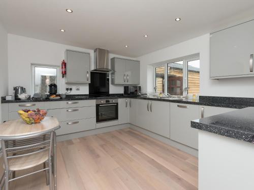 a kitchen with white cabinets and a wooden table at Inverspey in Kingston