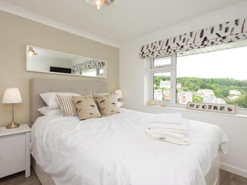 a white bedroom with a large bed and a window at Rockmount 1 in Salcombe