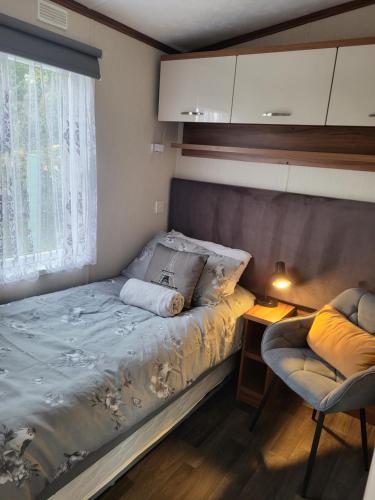 a small bedroom with a bed and a window at Elegant 2 Bedroom En-Suite Caravan with Bathtub near Edinburgh Seton Sands Holiday Village in Port Seton