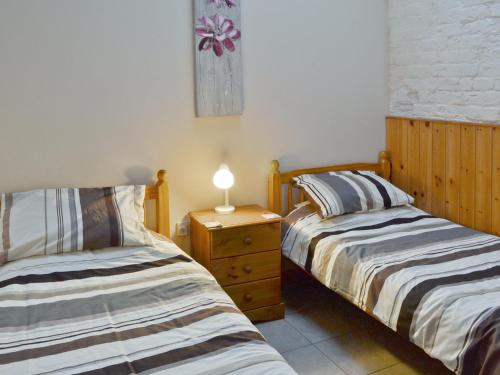 two beds in a room with a lamp on a night stand at Jenny Wren in Flamborough