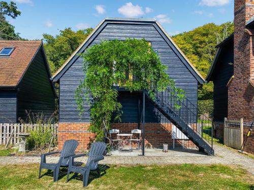 a black house with two chairs and a table at Wysteria, North Lodge in Rusper