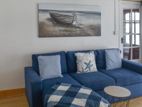 un sofá azul en una sala de estar con una pintura en Angie's Beachside House, en Brightlingsea