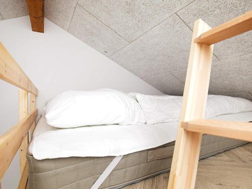 a bed in a loft with white pillows at 12 person holiday home in Millinge in Millinge