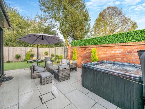 a patio with a hot tub and chairs and an umbrella at Foreman's Cottage in Skidby