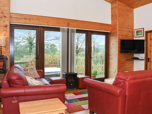 a living room with red leather furniture and glass windows at Ash Lodge - Hw7442 in Nantmel