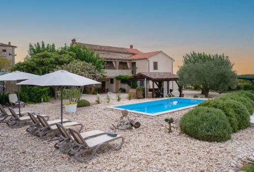 a backyard with a swimming pool and chairs and an umbrella at Lavanda Apartments & Room in Sveti Lovreč Pazenatički